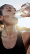 © Teeradej - Woman in athletic wear drinks water from bottle, refreshing herself after exercise under sun