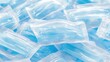 © dedikurniastudio - A pile of individually sealed medical face masks in clear plastic packaging with a blue tint