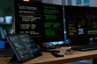© Mediaphotos - Closeup showing digital tablet and two computer monitors displaying programming code on wooden desk in workspace, electronic components and stylus lying nearby, no people