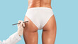 © Prostock-studio - Doctor drawing marks on female buttocks, preparing for cosmetic surgery operation isolated on blue studio background. Young lady getting ready for aestetic procedure, gluteal lipolysis, rear back biew