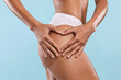 © Prostock-studio - Love Yourself Concept. Closeup cropped view of unrecognizable slim woman making heart sign gesture with hands on her buttocks isolated over blue studio background, banner. Anti cellulite massage