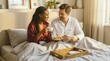 © Running opossum - couple enjoying breakfast in bed with coffee and pastries on a cozy weekend morning