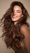 © Newleks - Happy woman with beautiful long wavy brown hair laughing and smiling while posing in a studio, expressing joy, natural beauty, and positive emotion