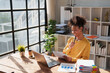 © Tj - Young happy African American woman reviewing financial documents and planning strategy at her desk, with a laptop and organized files in a modern office environment