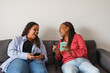 © Sabrina - Happy african mother and daughter having fun watching videos on social media with mobile phones at home - Technology, family and lifestyle concept