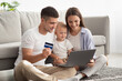© Prostock-studio - Happy Young Family Of Three With Little Infant Baby Using Laptop And Credit Card For Online Shopping At Home, Cheerful Millennial Parents And Their Toddler Child Enjoying Purchasing In Internet