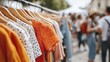© Viktoriia - Colorful polka dot dresses on hangers at outdoor market with blurred crowd in background