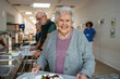© Halfpoint - Group of seniors having lunch in community center cafeteria.