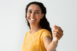 © Prostock-studio - Happy Young Lady Holding Invisible Object In Hand And Showing It At Camera, Cheerful Millennial Middle Eastern Woman Demonstrating Empty Space For Your Design And Mockup, Selective Focus