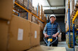 © Halfpoint - Older male warehouse worker pulling a pallet truck.