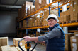 © Halfpoint - Older male warehouse worker pulling a pallet truck.