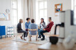 © Halfpoint - Group of people sitting in a circle and sharing experiences during guided therapeutic session.