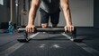 © thanawat - A person performing push-ups using a bar on a gym floor, showcasing strength training in a fitness environment.