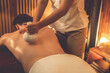 © InfiniteFlow - Hot herbal ball spa massage body treatment, masseur gently compresses herb bag on man body. Tranquil and serenity of aromatherapy recreation in warm lighting of candles at spa salon. Quiescent