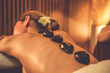 © InfiniteFlow - Hot stone massage at spa salon in luxury resort with warm candle light, blissful woman customer enjoying spa basalt stone massage glide over body with soothing warmth. Quiescent