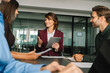 © Stock 4 You - Mature female mentor leader Latin woman collaborating with European young team doing banking analysing in office. Teamwork of professional business people working discussing financial trade strategy