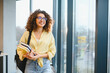 © Serhii - Smiling student carrying books arriving at university building