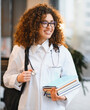 © Serhii - Female medical student smiling wearing lab coat and books