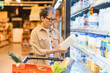 © Serhii - Senior woman shopping for dairy products in supermarket aisle