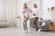 © New Africa - Happy senior couple dancing together at home. Space for text