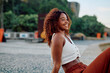 © we.bond.creations - Young Black woman with curly hair smiling outdoors, embodying joy and casual summer lifestyle in an urban setting