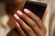 © john - Close-up: african female hand with long pink nails holding smartphone during incoming call