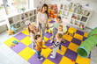 © Pixel-Shot - Group of little children with nursery teacher holding hands in kindergarten, top view
