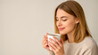 © NikProArt - Young woman enjoying the comforting aroma of a hot coffee mug.