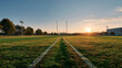 © Tiwakeat - Symmetrical front view of empty school field at sunrise with green grass and goalpost