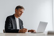 © sam richter - Mature businessman types on laptop at desk in bright office.​