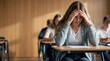 © Volha - Stressed student sitting exam in classroom