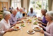 © Marina Shvedak - Group of diverse senior men and women enjoy a meal together at a retirement home. Healthy eating for elderly people concept.
