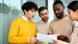 © Halyna - Diverse group of business people analyzing a document in a modern office. Multi-ethnic team of colleagues reviewing a report together. Teamwork and collaboration concept
