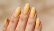 © willem - Close-up of a hand with butter yellow painted nails against a blurred beige background