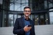 © ffunn - Confident businessman using smartphone in city business communication and technology.