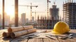 © Tina - Construction site with blueprints, a yellow hard hat, and tools on a wooden table. Skyscrapers and cranes are visible in the background during sunset.