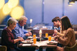 © .shock - Family enjoys iftar meal in a restaurant during Ramadan with decorations and warm lighting in the background