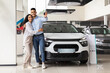 © Prostock-studio - Cheerful young arab man and woman posing over their new auto in showroom, showing key from luxury automobile and hugging, copy space. Middle-eastern family buying new comfortable car