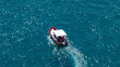 © Stefano Tammaro - High-angle shot of a small wooden boat with a white canopy cruising through sparkling turquoise water, leaving a gentle white wake on the sun-dappled sea surface. Aerial view of a boat in the sea.