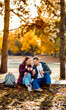 © Zoran Zeremski - Romantic young multiracial couple enjoying a date in an autumn park, sitting on grass drinking tea.