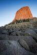 © Mint Images - Devil's Tower glows orange in the evening light, rising above rocky slopes and pine trees in northeastern Wyoming.