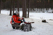 © Наталья Николаева - A man in an orange jacket pours tea from a thermos into a tin mug in a winter forest.