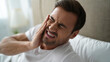© olgakris - Man suffering from toothache with facial tension in bed, bruxism and TMJ migraine, sleep apnea connection, facial muscle stress impact, nervous system regulation challenges