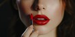 © Alexandr Efimov - A woman with dark hair and red lips applies lipstick close up. She is wearing makeup which includes eye shadow and mascara.