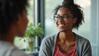 © miss irine - Two young women talk happily in cafe. One smiles broadly, wearing glasses. They share ideas and connect, building friendship and mutual understanding in relaxed setting.