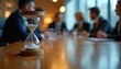 © miss irine - Hourglass on meeting room table signifies time passing for business team. Urgency, deadlines, planning, and productivity are key concepts for corporate success.