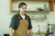 © Ekkasit A Siam - Senior Caucasian male barista wearing brown apron standing behind counter looking down with serious thoughtful expression inside small cozy cafe reflecting on work tasks., Concept small business