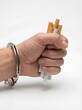 © Christian - Handcuffed hand gripping a bundle of cigarettes, representing smoking addiction