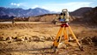 © Adib - A surveying instrument is set up on a construction site, with a blurred background of mountains and earthworks under a bright sky