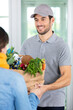 © auremar - deliveryman in uniform giving bag of food to customer